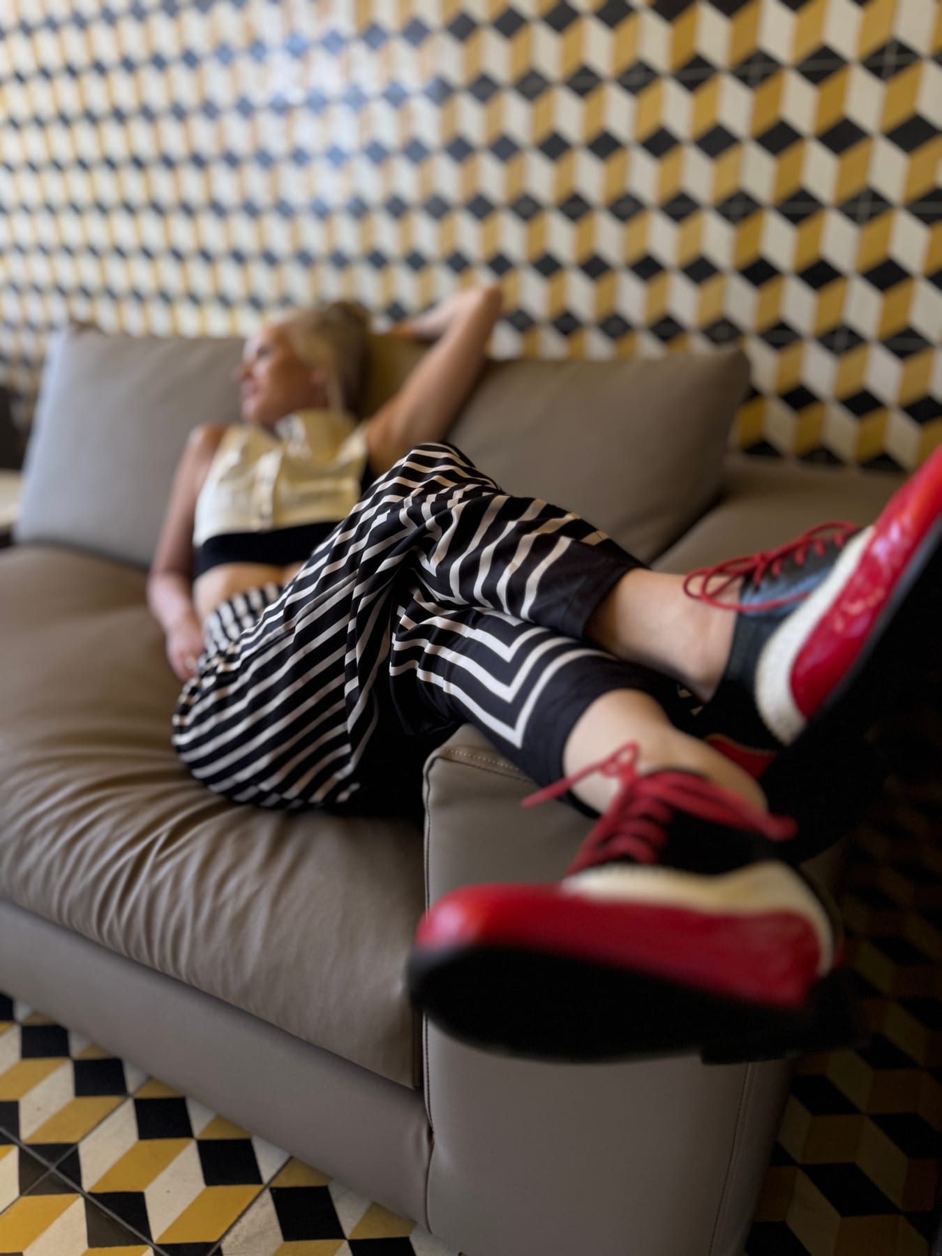 Janelle relaxing on a sofa with striped trousers and red-and-black shoes